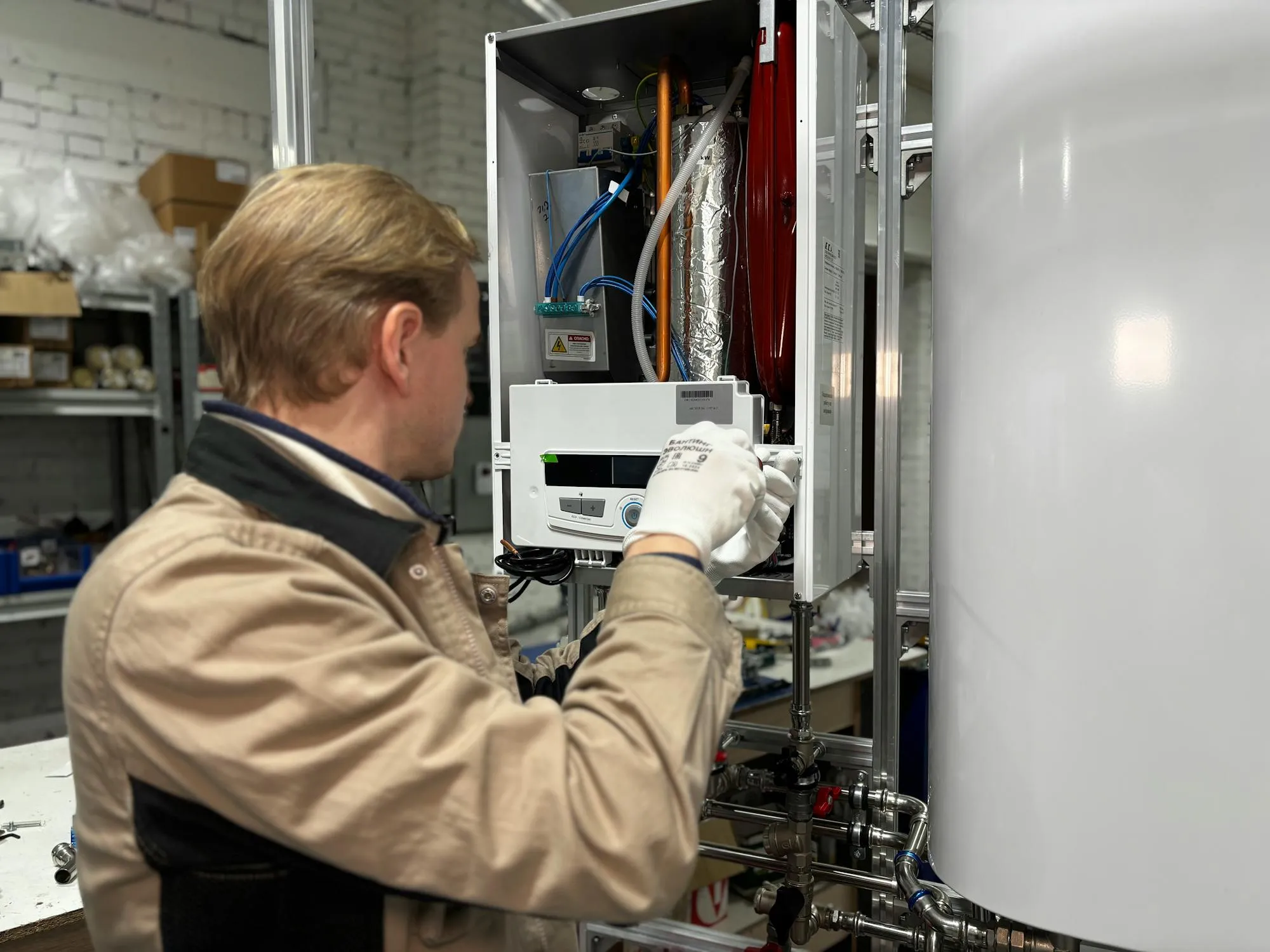 Heating engineer in workwear adjusting a domestic boiler control panel